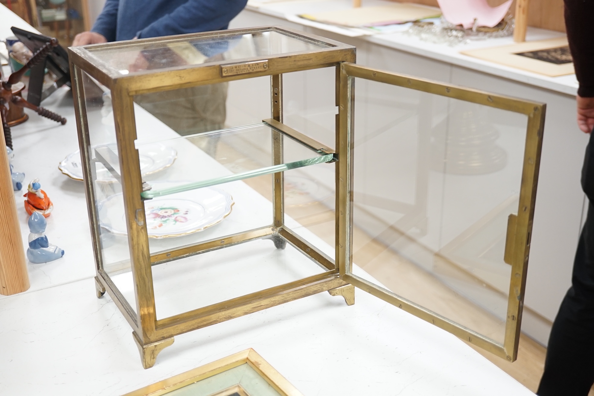 A small late 19th century brass display case, with glass shelf, bears plaque 'J Weiss & Son, 287 Oxford Street, London